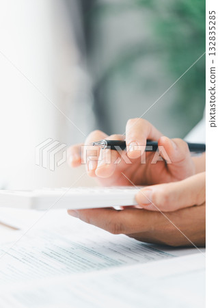 Concept of financial planning and accounting. A businesswoman uses a calculator to analyze reports and charts, calculating budget and investment strategy with focus and precision at office desk. Concept of financial planning and accounting. A businesswoman uses a calculator to analyze reports and charts, calculating budget and investment strategy with focus and precision at office desk. 132835285