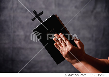 Bible in hand, christian lifts prayer in worship, holding firmly to holy concept of faith, hope and deep belief guides their spiritual life. Hands together in prayer to God along with bible Bible in hand, christian lifts prayer in worship, holding firmly to holy concept of faith, hope and deep belief guides their spiritual life. Hands together in prayer to God along with bible 132835409
