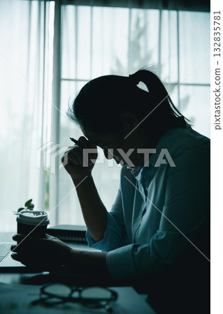 Stressed businesswoman working late at home office, feeling exhausted while reviewing financial documents on laptop. Concept of work stress, burnout, deadline, and overwork. Stressed businesswoman working late at home office, feeling exhausted while reviewing financial documents on laptop. Concept of work stress, burnout, deadline, and overwork. 132835781