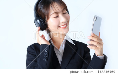 一位女上班族正在用智慧型手機聽音樂的圖片 132836569