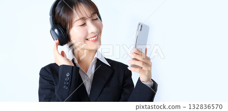 一位女上班族正在用智慧型手機聽音樂的圖片 132836570