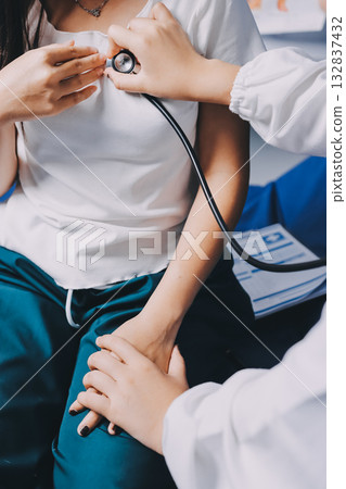 Doctor examining patient with stethoscope in hospital bed. Medical care and healthcare concept in a clinical setting. Doctor examining patient with stethoscope in hospital bed. Medical care and healthcare concept in a clinical setting. 132837432
