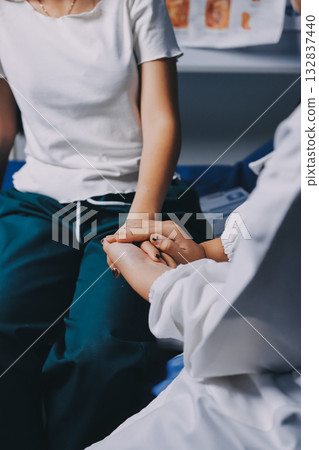 Doctor giving hope. Close up shot of young female physician leaning forward to smiling elderly lady patient holding her hand in palms. Woman caretaker in white coat supporting encouraging old person 132837440