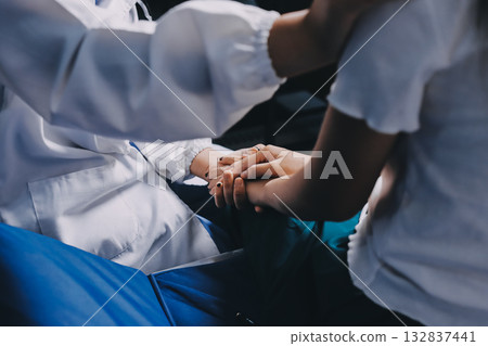 Doctor giving hope. Close up shot of young female physician leaning forward to smiling elderly lady patient holding her hand in palms. Woman caretaker in white coat supporting encouraging old person 132837441
