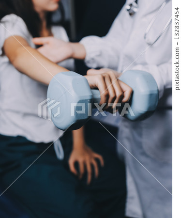 old woman training with physiotherapist using dumbbells at home therapist assisting senior woman with exercises in nursing home elderly patient using dumbbells with outstretched arms no logos no bran old woman training with physiotherapist using dumbbells at home therapist assisting senior woman with exercises in nursing home elderly patient using dumbbells with outstretched arms no logos no bran 132837454
