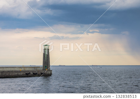 The coast of the Baltic Sea in northern Poland. Coastal beacon standing tall against a dramatic sky, guiding ships and sailors through the open water. Tranquil seascape scenery. The coast of the Baltic Sea in northern Poland. Coastal beacon standing tall against a dramatic sky, guiding ships and sailors through the open water. Tranquil seascape scenery. 132838513