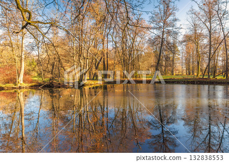 Autumn Reflections: Still lake mirrors the surrounding trees in their fall colors, creating a serene and beautiful landscape. 132838553
