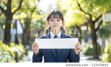 A high school girl in uniform holding a long blank piece of paper in front of her chest 132838693