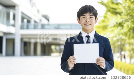 A male high school student in uniform holding a long blank piece of paper in front of his chest A male high school student in uniform holding a long blank piece of paper in front of his chest 132838696