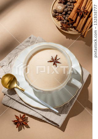 Traditional Indian masala chai tea with milk and spices in a cup on a beige background 132838777