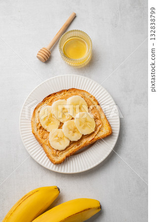 Peanut butter toast and banana in a white plate on a light background 132838799