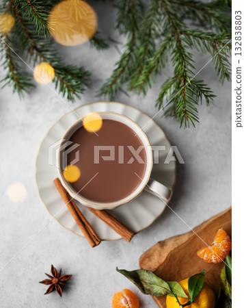 Hot chocolate in a cup against a light background with spices, fir branches, tangerines 132838803