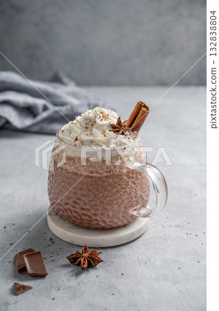 Hot chocolate in a cup with whipped cream and spices on a light background with napkin. 132838804