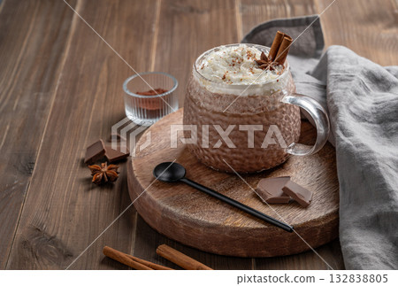 Hot chocolate in a cup with whipped cream and spices on a rustic dark wooden background. Hot chocolate in a cup with whipped cream and spices on a rustic dark wooden background. 132838805