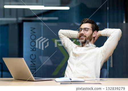Satisfied with work and relaxed young male businessman sitting in the office at the desk with his eyes closed and resting. Satisfied with work and relaxed young male businessman sitting in the office at the desk with his eyes closed and resting. 132839279