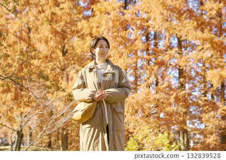 中年婦女在秋葉中行走 132839528
