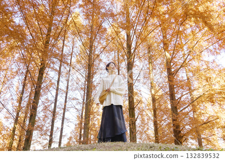 Middle-aged woman walking among autumn leaves Middle-aged woman walking among autumn leaves 132839532