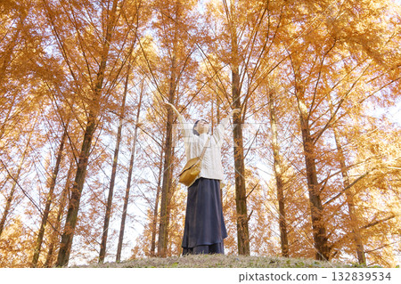 Woman taking a deep breath among autumn leaves, middle-aged, full body 132839534