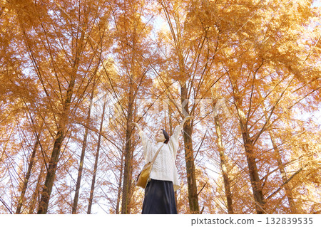 Woman taking a deep breath among autumn leaves, middle-aged, full body 132839535