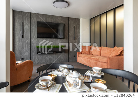 Stylish Living Room with Orange Sofa and Tea Set on Black Table Stylish Living Room with Orange Sofa and Tea Set on Black Table 132840264