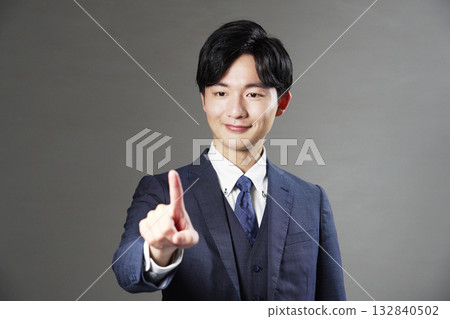 Businessman making a gesture of pressing a switch with his index finger, black background Businessman making a gesture of pressing a switch with his index finger, black background 132840502