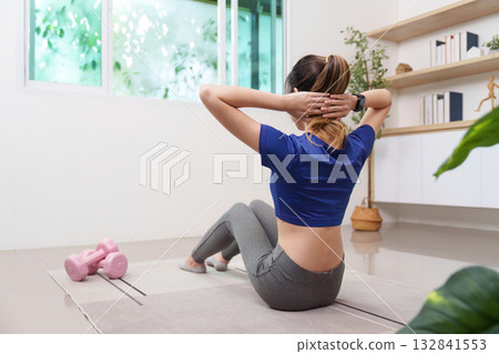Core Strength. Young woman performing sit-ups at home with weights. Core Strength. Young woman performing sit-ups at home with weights. 132841553