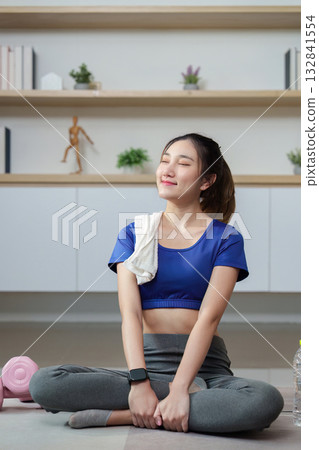 Home Fitness. Young woman enjoying a post-workout stretch with a towel. 132841554