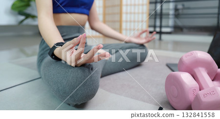 Mindfulness and Fitness: Woman Meditating with Dumbbells Nearby Mindfulness and Fitness: Woman Meditating with Dumbbells Nearby 132841558