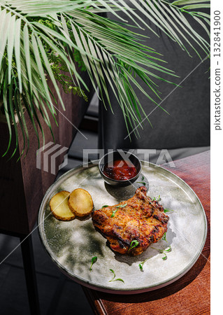 Juicy grilled pork served with sauce and garnishes in a cozy setting 132841900