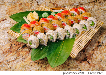Colorful sushi platter served on bamboo mat with fresh garnishes Colorful sushi platter served on bamboo mat with fresh garnishes 132841925
