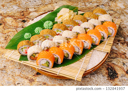 Fresh sushi platter featuring various rolls and garnishes on a wooden tray Fresh sushi platter featuring various rolls and garnishes on a wooden tray 132841937