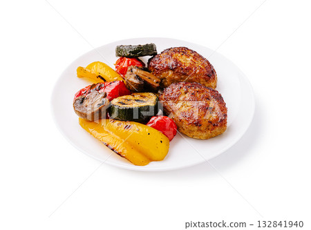 Grilled chicken patties served with colorful roasted vegetables on a plate 132841940