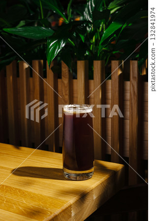 Refreshing drink served in a glass on a wooden table in a cozy setting Refreshing drink served in a glass on a wooden table in a cozy setting 132841974