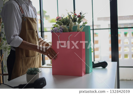 A small business owner, a florist or a gift shop worker preparing a customer's order. A small business owner, a florist or a gift shop worker preparing a customer's order. 132842039