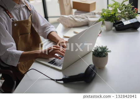 A small business owner, a florist or a retailer of plants working on a laptop managing orders for startup or an online business.  132842041