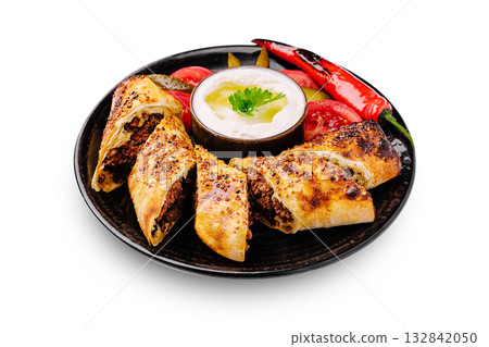 Savory meat rolls with fresh vegetables and yogurt dip on a black plate 132842050