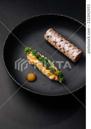 Gourmet dish featuring seafood and vegetable garnishes on a black plate Gourmet dish featuring seafood and vegetable garnishes on a black plate 132842053
