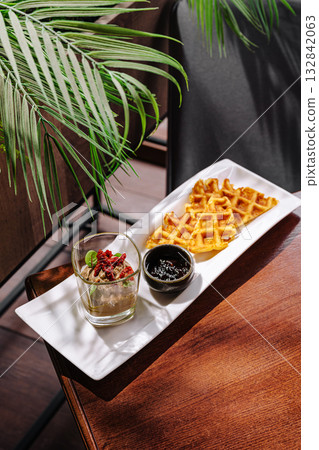 Delicious waffles served with a sweet sauce and dessert in a cozy cafe Delicious waffles served with a sweet sauce and dessert in a cozy cafe 132842063