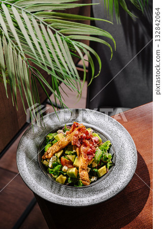 Fresh salad with grilled chicken and toppings in a cozy dining setting 132842064