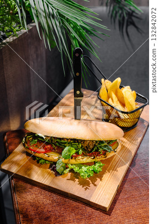 Fresh sandwich and crispy fries served on a wooden board in a cafe setting 132842072