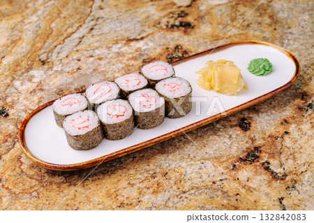 Delicious sushi rolls arranged elegantly on a plate with condiments 132842083