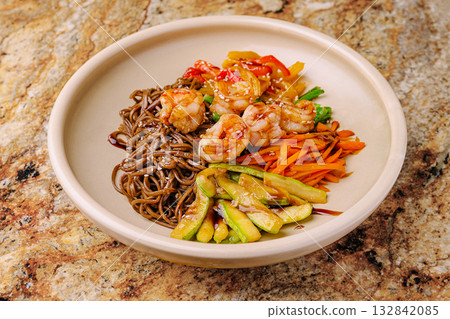Delicious shrimp and vegetable stir fry served over soba noodles in a bowl Delicious shrimp and vegetable stir fry served over soba noodles in a bowl 132842085