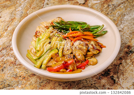 Delicious vegetable stir-fry served in a bowl on a colorful countertop Delicious vegetable stir-fry served in a bowl on a colorful countertop 132842086