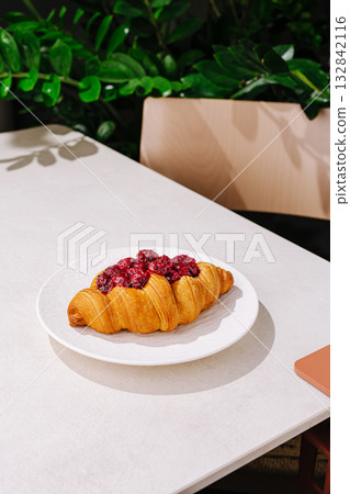 Fresh croissant with berry topping on a white plate at a caf? table 132842116