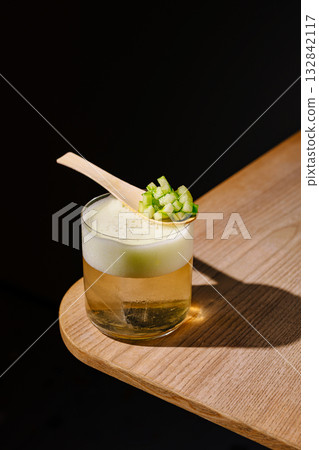 Unique cocktail served in glass with cucumber on wooden spoon for presentation Unique cocktail served in glass with cucumber on wooden spoon for presentation 132842117