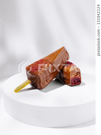 Chocolate popsicle placed on a white circular stand 132842124