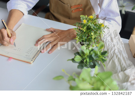 A florist  taking notes planning for the shop order and inventory. 132842187