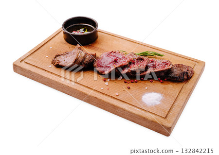 Savory beef steak sliced on wooden board with sauce and seasonings Savory beef steak sliced on wooden board with sauce and seasonings 132842215