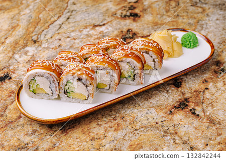 Sushi rolls served on a plate with ginger and wasabi on a textured table 132842244
