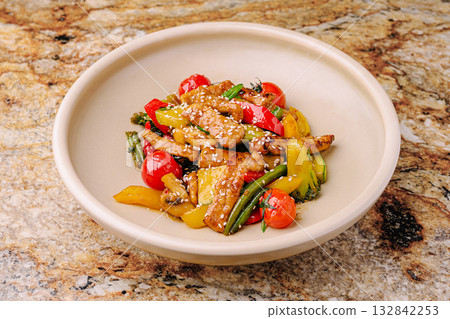 Colorful stir-fried vegetables with chicken served in a bowl on a stone surface Colorful stir-fried vegetables with chicken served in a bowl on a stone surface 132842253
